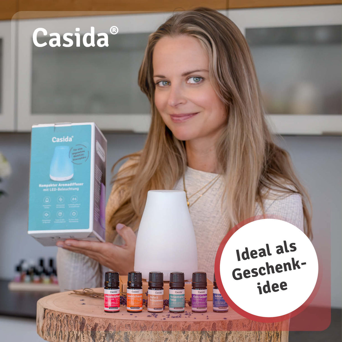A woman holding a compact aroma diffuser set with essential oils on a wooden surface, featuring various colored bottles.