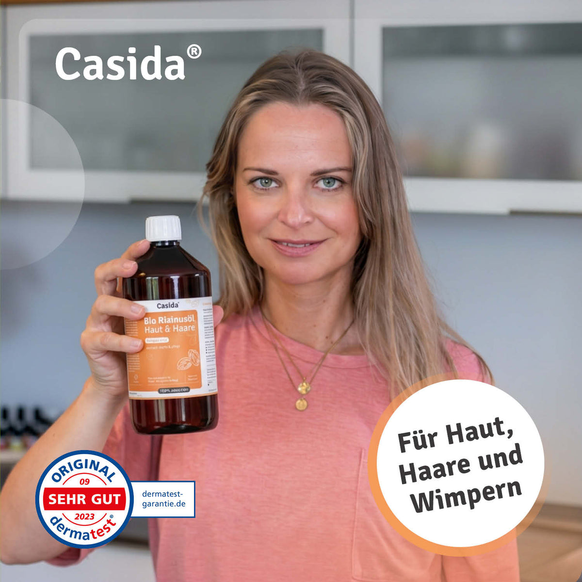 Frau präsentiert eine große Flasche Casida Bio Rizinusöl neben einem Dermatest-Siegel