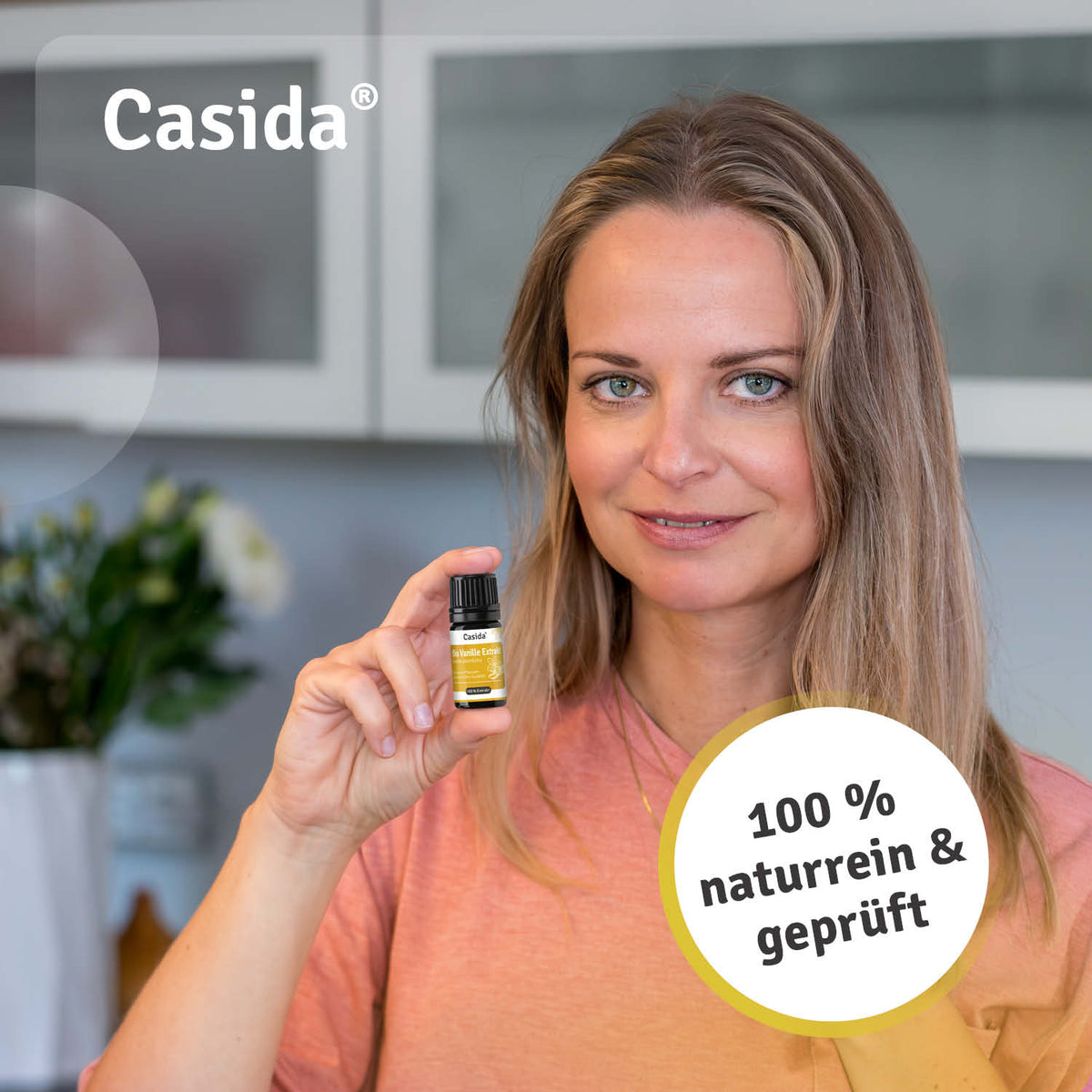 Casida bio vanilla extract bottle held by a woman, featuring a yellow label and text stating "100% naturrein & geprüft.
