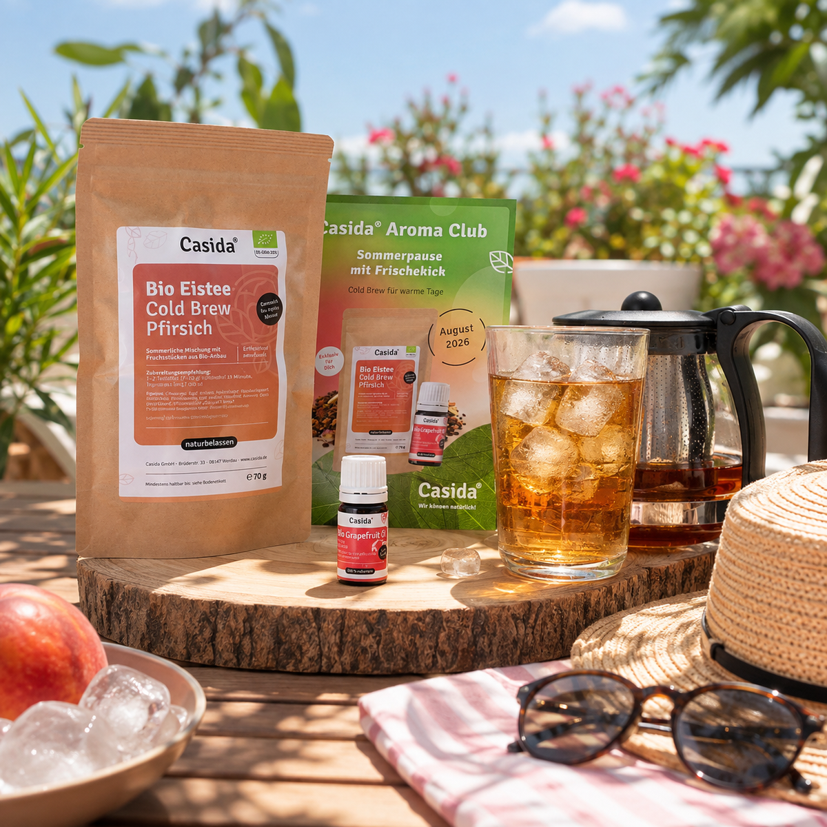 Casida Aroma Club Sommerbox mit Bio Pfirsich-Eistee, Duftöl und Glaskanne auf einer Terrasse