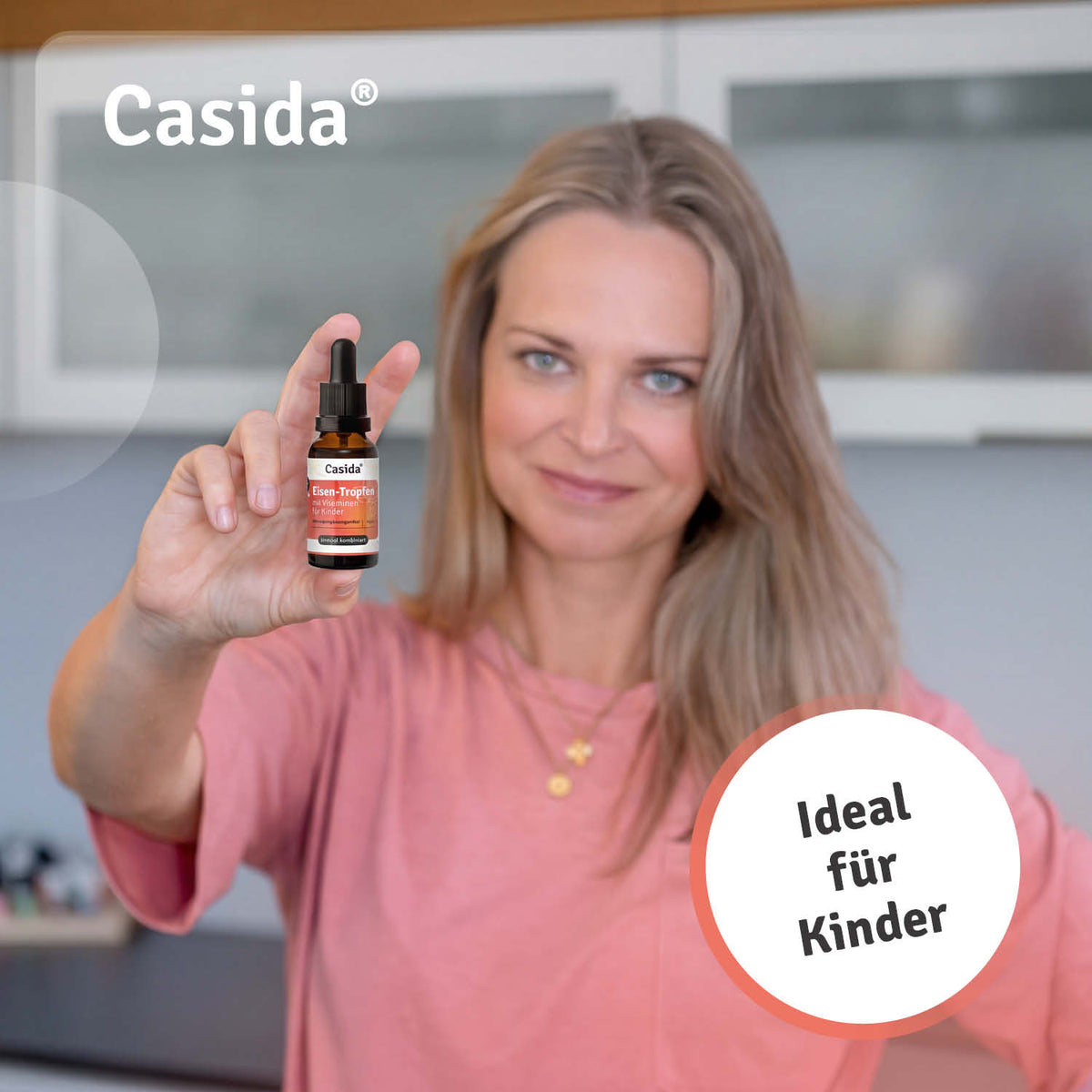 Casida Eisen Tropfen für Kinder in einer Hand, mit orangefarbenem Etikett und weißem Hintergrund.