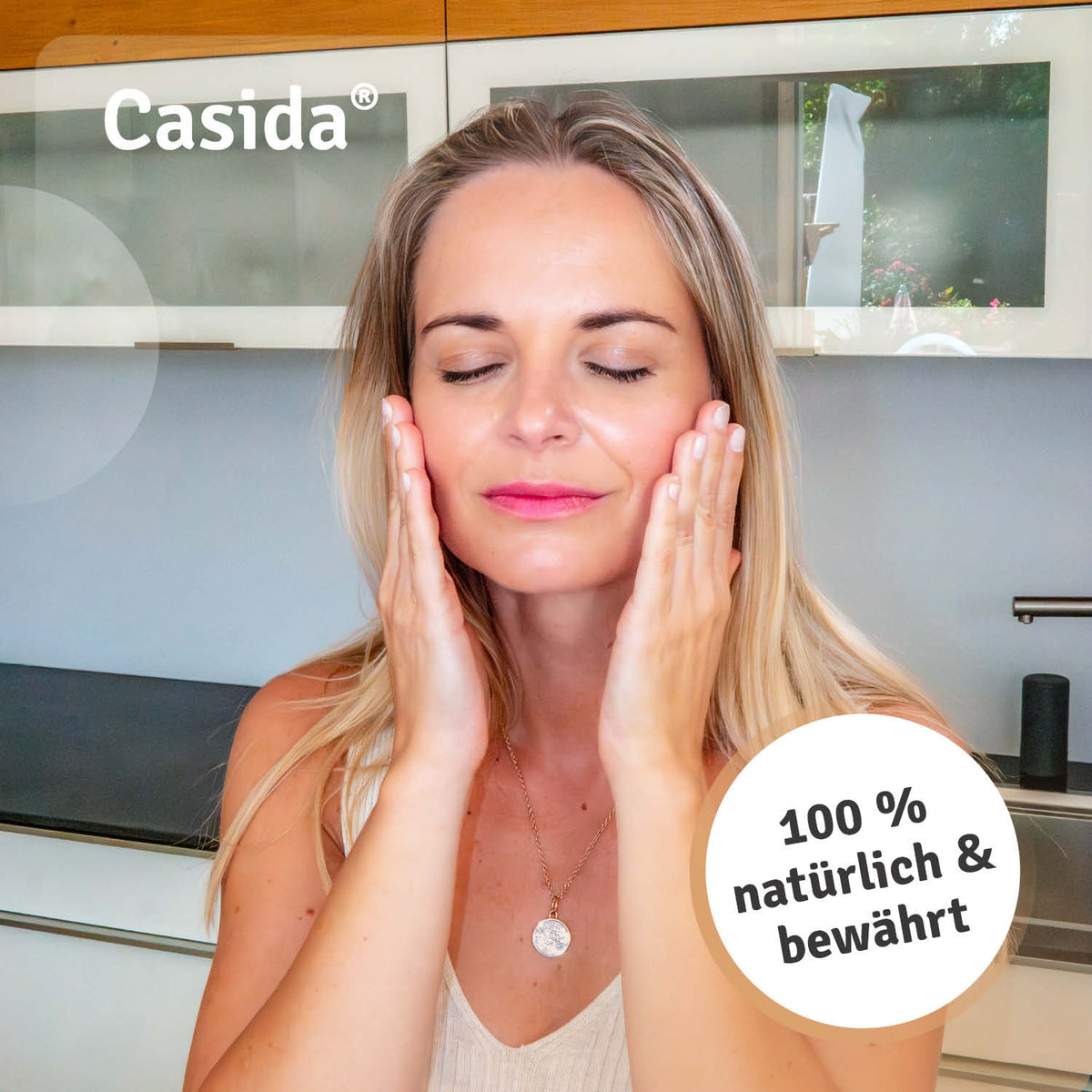 Casida Gelassenheit & Ruhe Körperöl, a woman applying oil to her face in a modern kitchen setting.