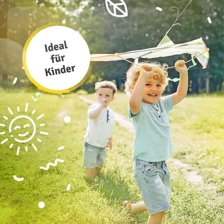 Zwei Kinder spielen mit großen Seifenblasen auf einer sonnigen Wiese