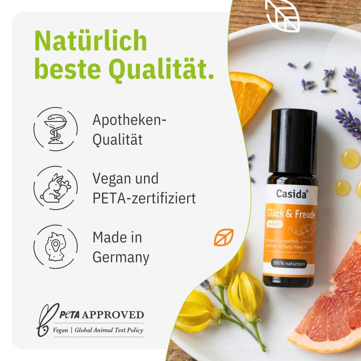 Glück & Freude roll-on bottle with orange label, surrounded by flowers and herbs on a white plate.