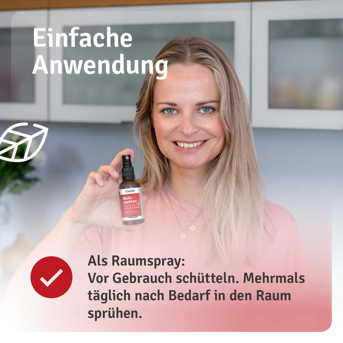 Weihnachten Raumspray in a black bottle held by a woman, with usage instructions visible in the background.