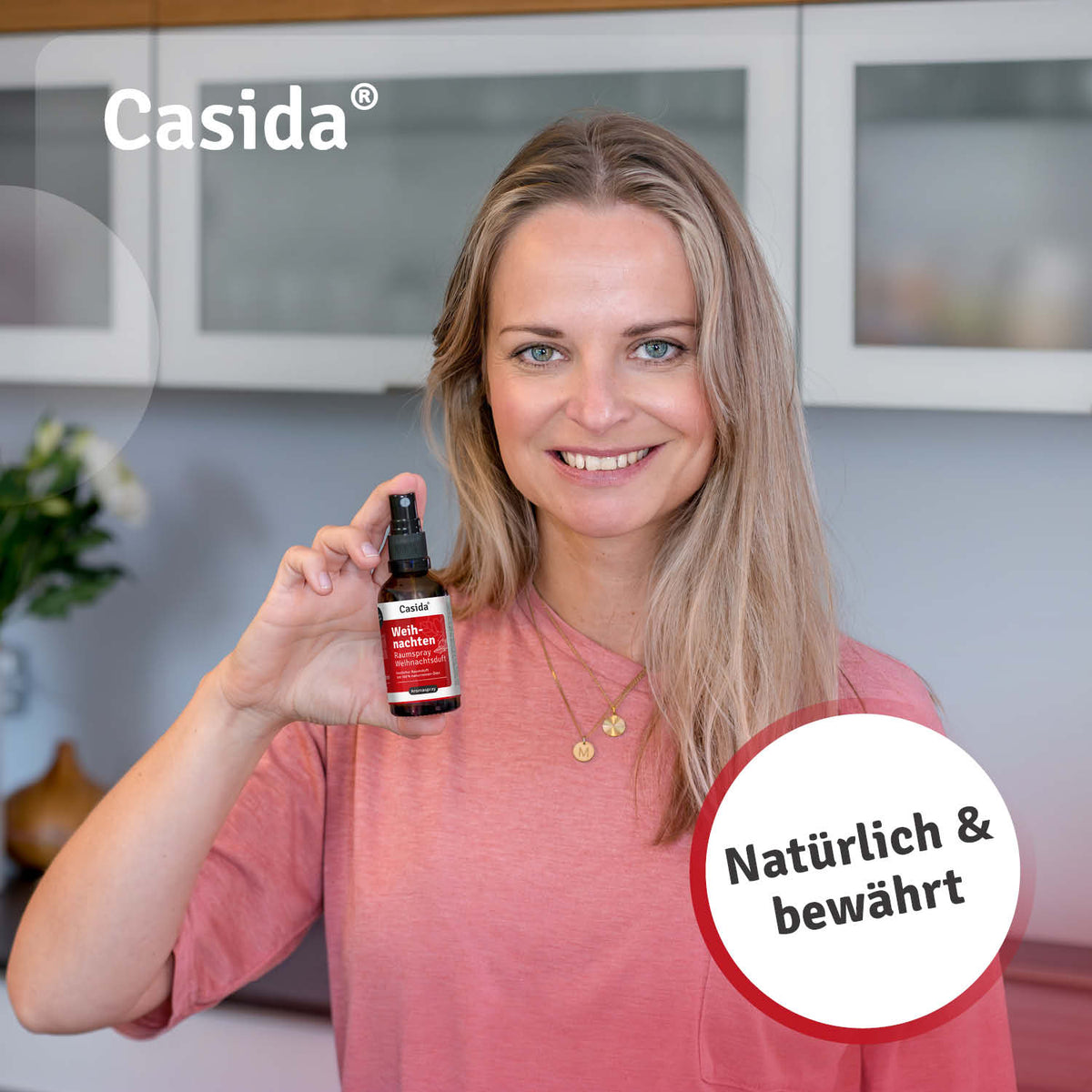 Casida Weihnachten raumspray in a woman's hand, featuring a red label and a spray bottle design.