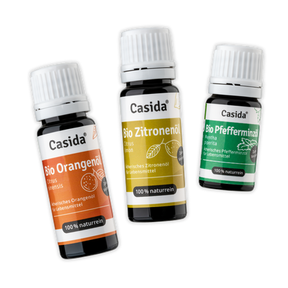 Set of three organic essential oils: lemon, orange, and peppermint in dark bottles with labels.
