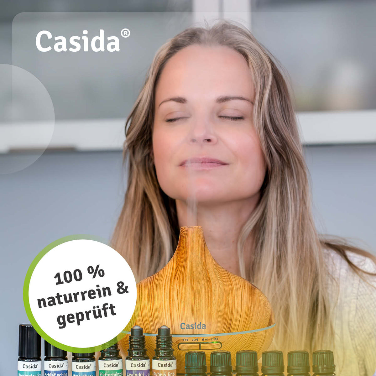 Frau mit geschlossenen Augen hinter einem Diffuser in Holzoptik und dem Casida Sommer-Öle-Set