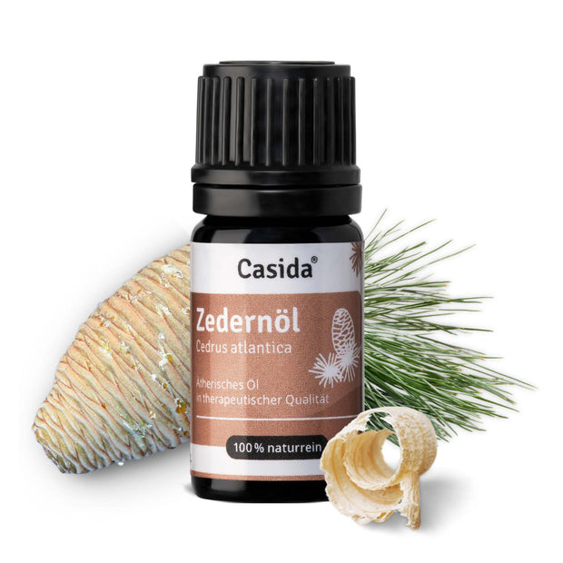 Zedernöl by Casida in a dark bottle, with cedar cone and wood shavings beside it, showcasing natural ingredients.